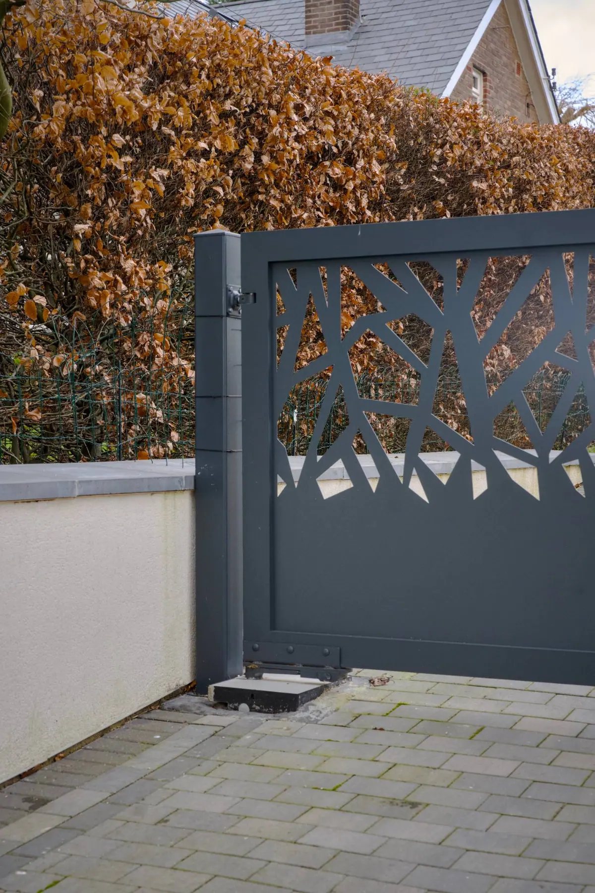 Grey manual gate with a laser-cut branch pattern