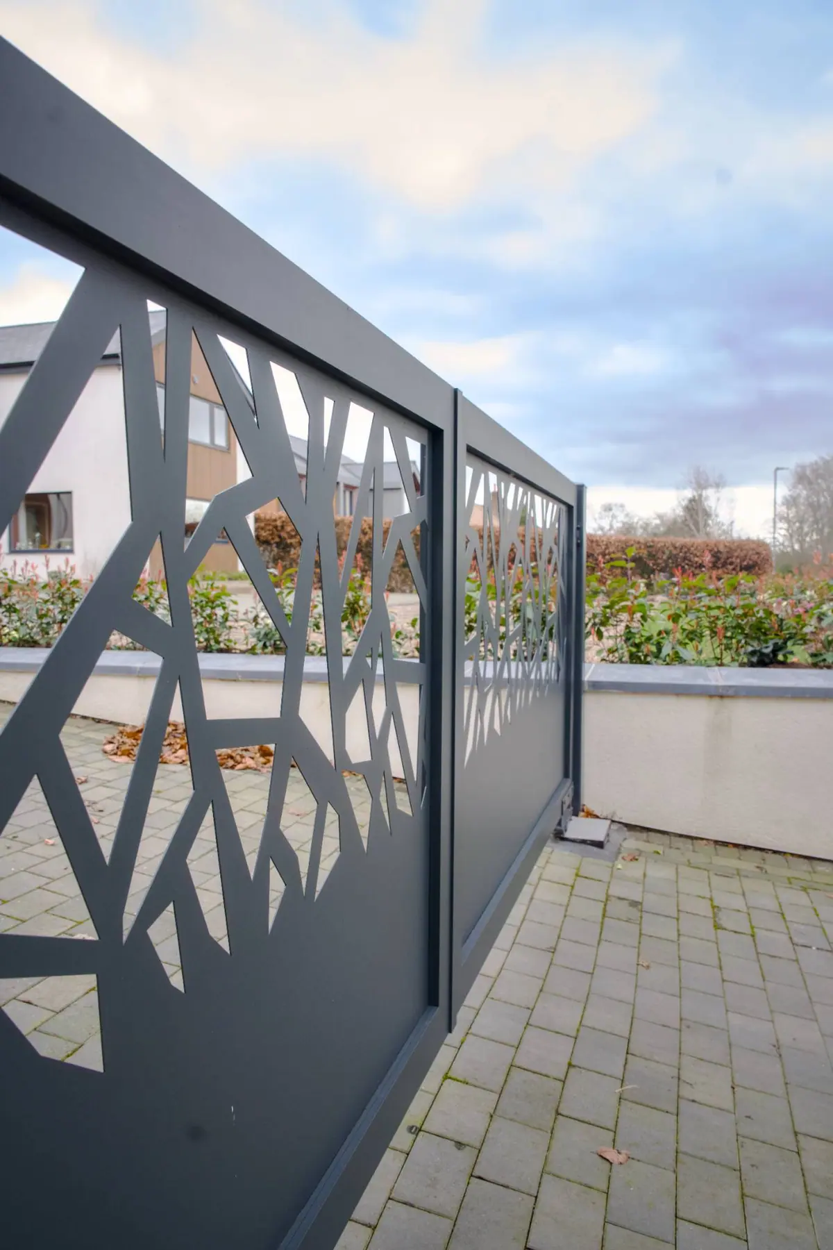 Grey manual gate with a laser-cut branch pattern