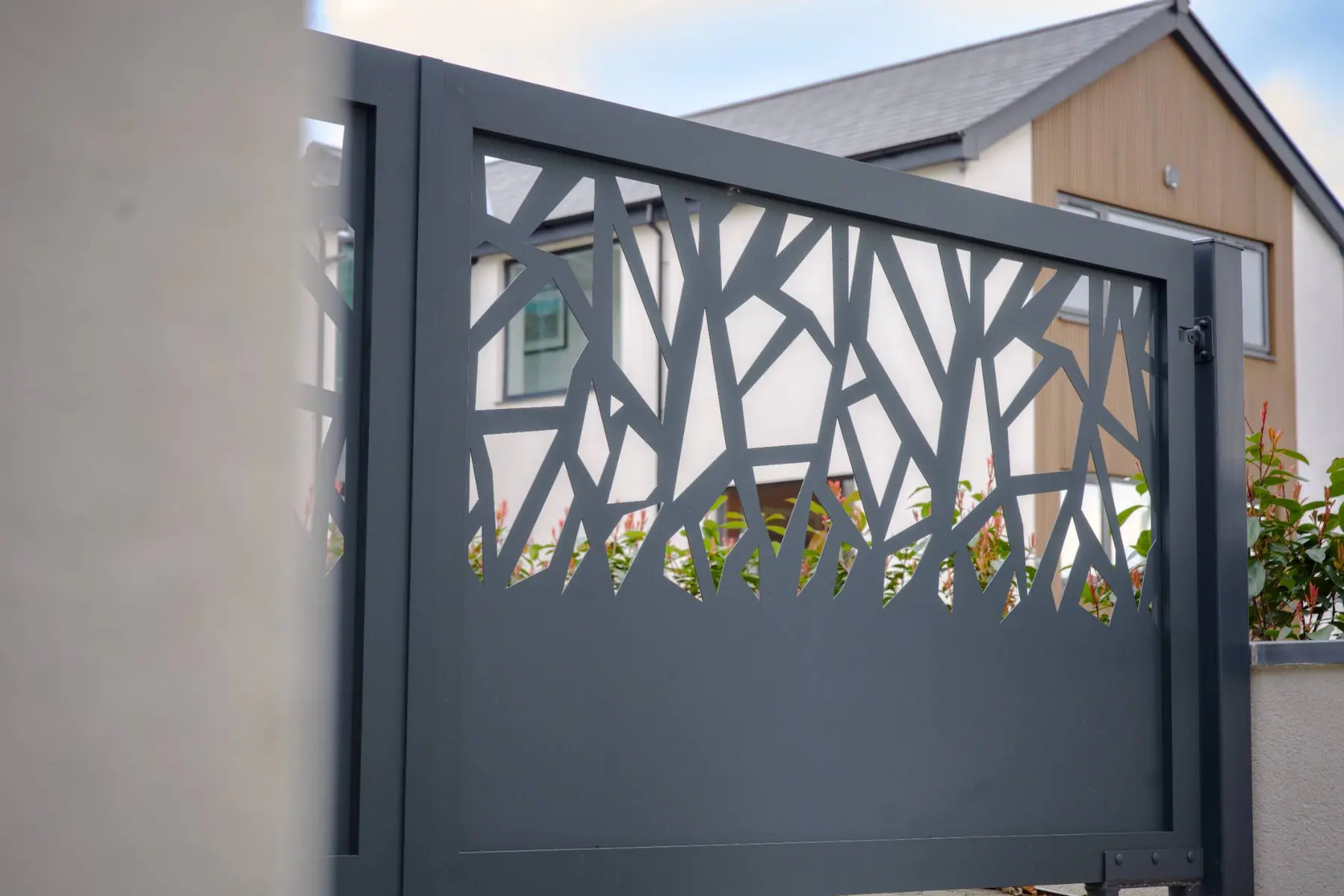 Grey manual gate with a laser-cut branch pattern