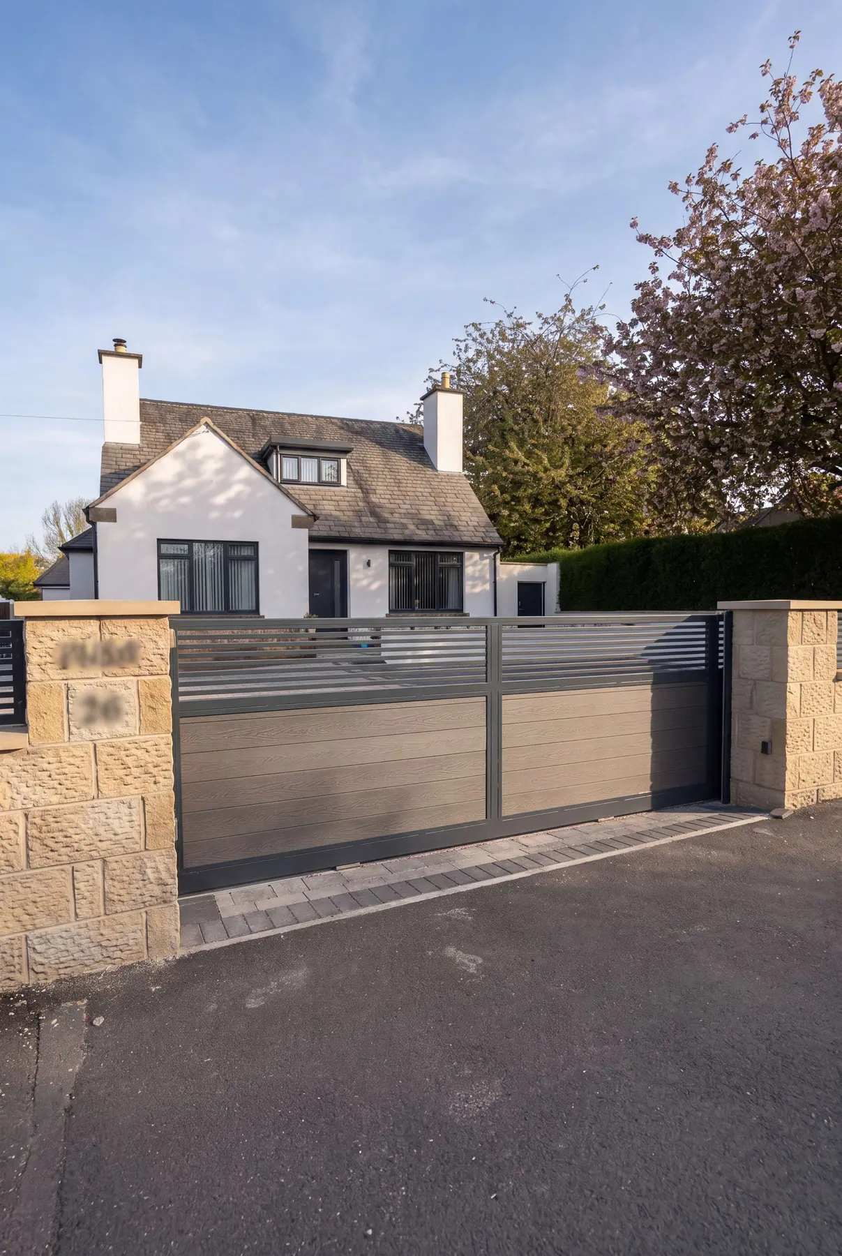 Composite driveway gates with a slatted top panel, between sandstone pillars at a Yorkshire home