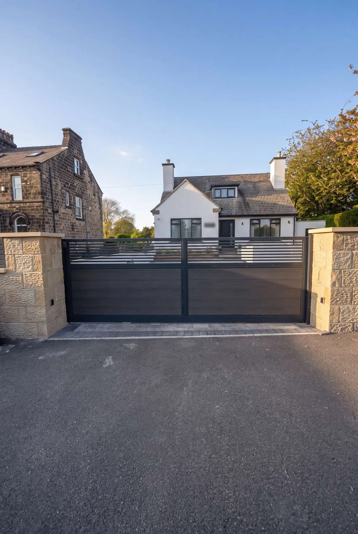 Composite driveway gates with a slatted top panel, between sandstone pillars at a Yorkshire home